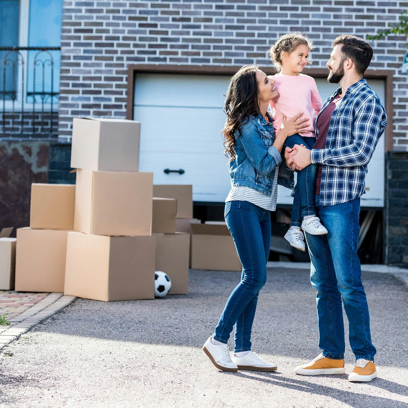 A family standing in front of their new home with moving boxes