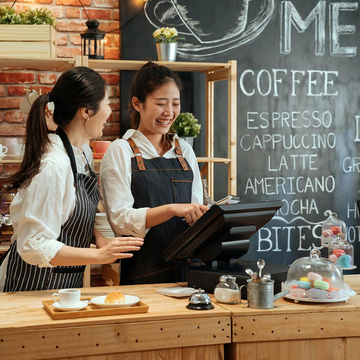 Two employees working a cash register in a cafe 