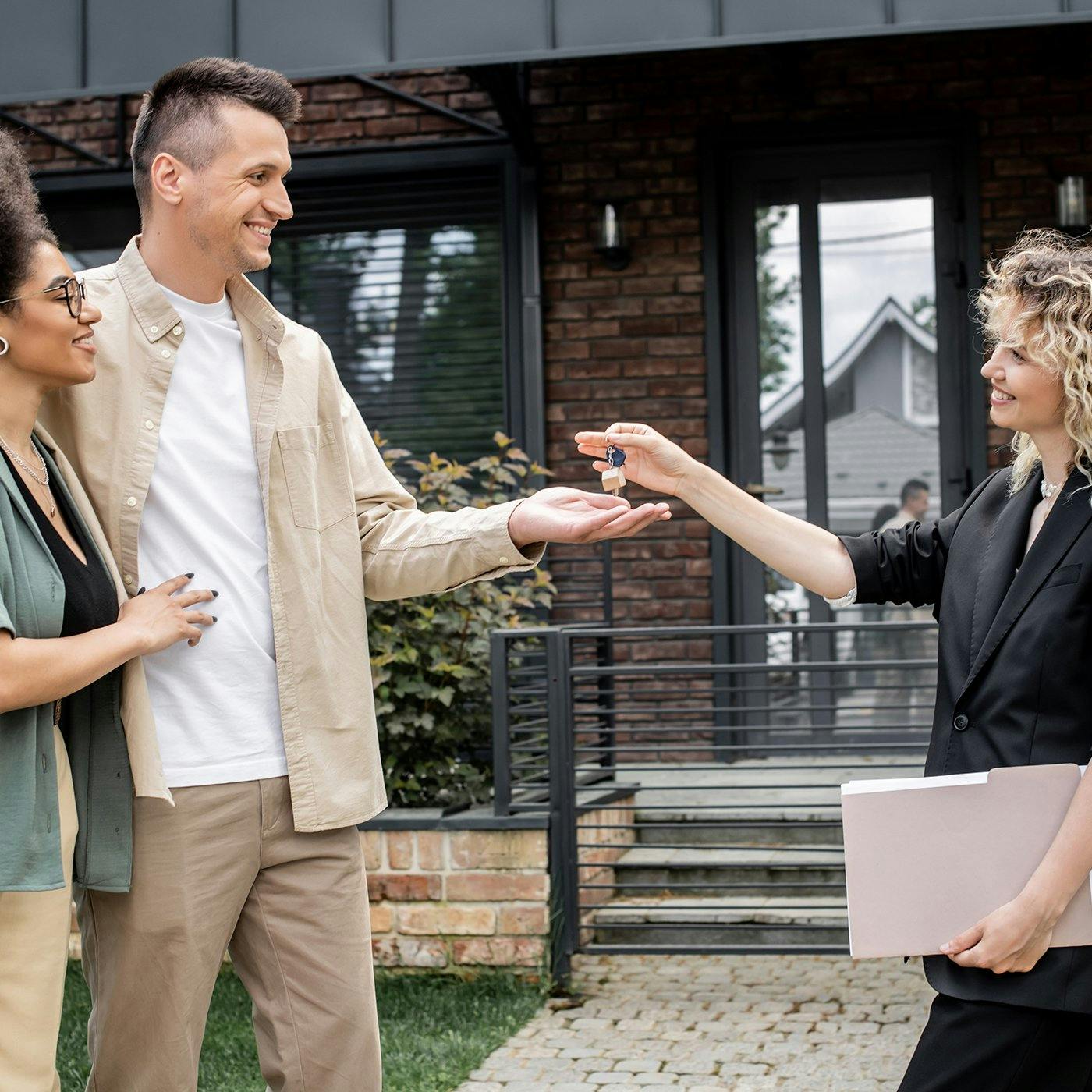 A couple receiving a pair of keys from a realtor