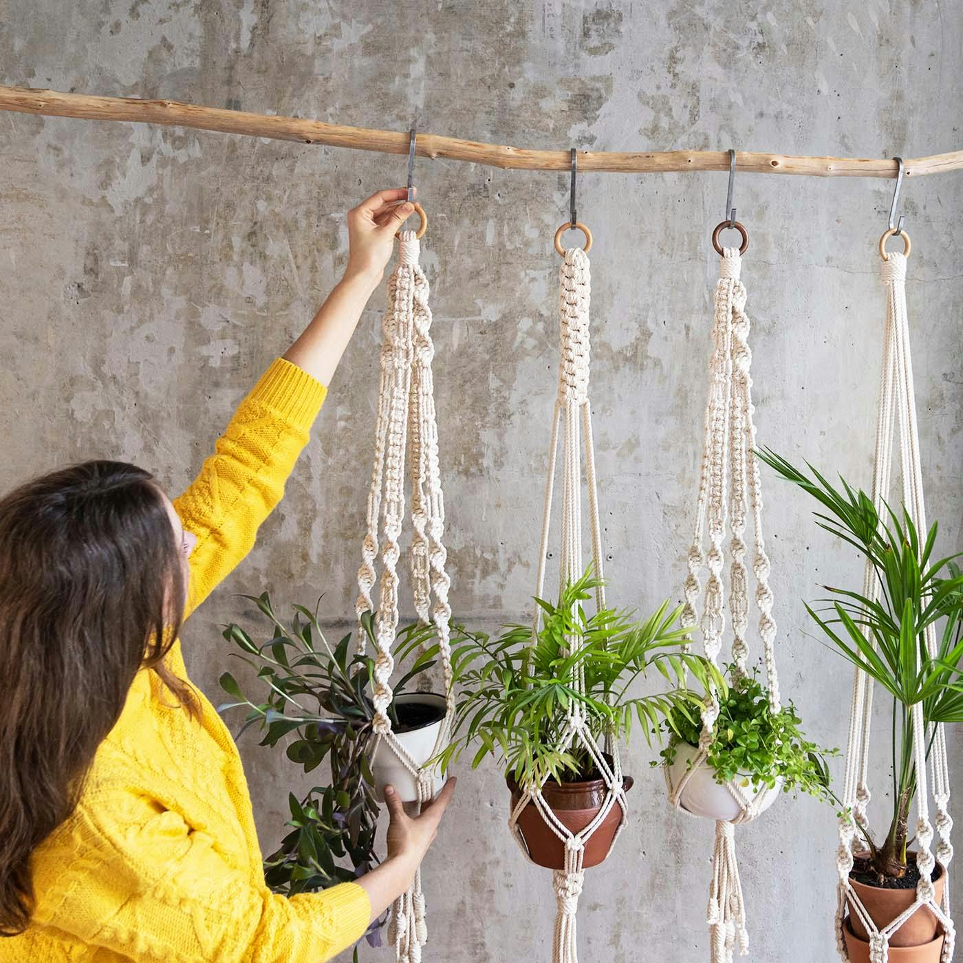 A woman hanging plants in a home